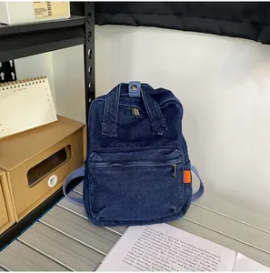 Detailansicht eines dunkelblauen Denim-Rucksacks mit orangefarbenem Etikett in Büroumgebung