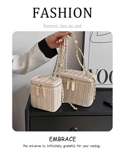 Détail d'un sac boîte tissé avec bandoulière réglable dorée et fermeture éclair