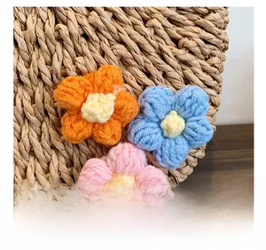 Detail of hand-woven straw bag featuring three colorful crochet floral decorations