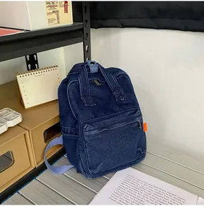 Detailansicht eines dunkelblauen Jeansrucksacks mit auffälligem orangefarbenem Webetikett