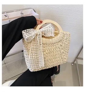 Detail of hand-woven straw tote with wooden handle, floral lace bow, and drawstring liner