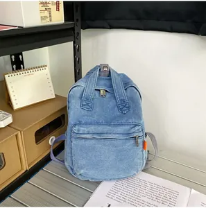 Nahaufnahme des Denim-Rucksacks mit verstärkten X-Nähten und orangefarbenem Markenetikett