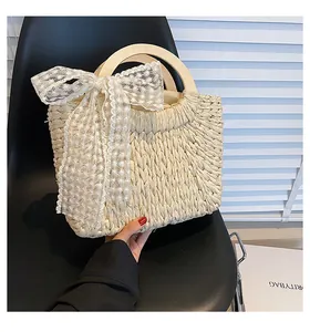 Close-up of woven straw bag featuring round wooden handles and white lace floral bow