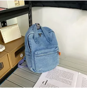 Detailansicht hellblauer Denim-Rucksack mit lavendelfarbenen Trägern auf dem Schreibtisch