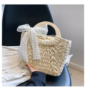 Detail of woven straw tote bag with round wooden handle and white floral lace ribbon