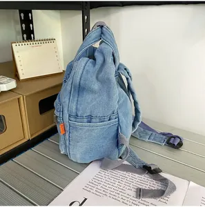 Detail eines blauen Denim-Minirucksacks mit orangefarbenem Etikett und Nylonriemen