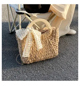 Detail of hand-woven straw bag featuring wooden handles and delicate white lace bow