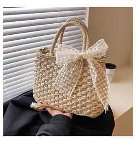 Vue détaillée de la texture du sac en paille avec élégant nœud en dentelle blanche