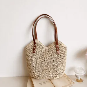 Dettaglio della borsa shopper in paglia intrecciata con manici in pelle marrone
