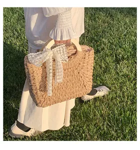 Detail of straw woven bag with wooden handles and delicate daisy lace bow decoration