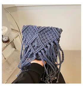 Dettaglio della trama geometrica fatta a mano e nappa sulla borsa in cotone grigio-blu