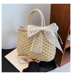 Détail du nœud en dentelle blanche et de la paille tressée naturelle du sac de plage été