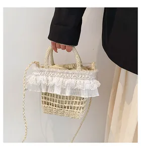 Détail du sac seau en paille tissée avec bordure en dentelle blanche et cordon intérieur
