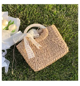 Close-up of a woven straw handbag with a white lace bow on fresh green grass