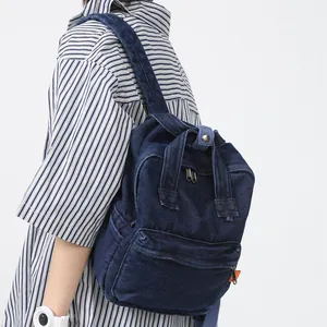 Klassischer dunkelblauer Denim-Rucksack mit Reißverschlusstasche, präsentiert am Modell