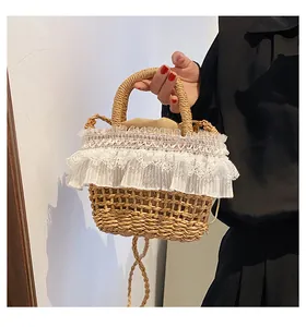 Détail d'un sac seau en paille tressée avec dentelle blanche et poignée robuste