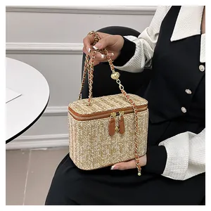 Détail du sac boîte en paille tissée avec garniture en cuir brun et dorures
