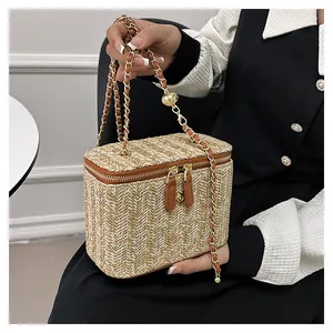 Détail du sac vanité en paille tressée avec double zip et bandoulière chaîne dorée