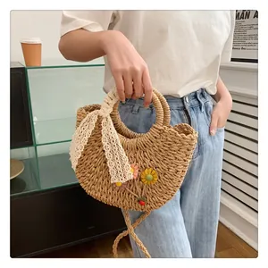 Detail of hand-woven straw bag with colorful floral appliques and white lace ribbon