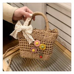 Detail of woven straw handbag featuring lace bow and handmade floral crochet charms
