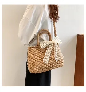Mannequin portant un sac en paille tressée avec nœud en dentelle blanche pour les vacances