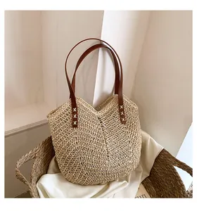 Dettaglio della borsa in paglia intrecciata a mano con spalline in pelle marrone e motivo a V