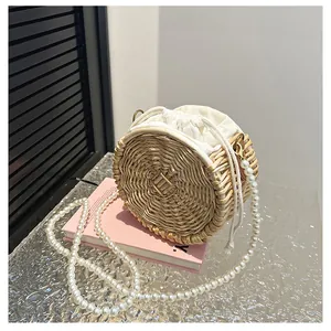 Detail van ronde strooien tas met elegante parelketting en voering met trekkoord