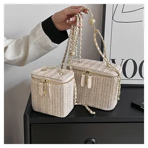 Détail de sacs boîtes en paille tressée avec chaînes et boules dorées réglables