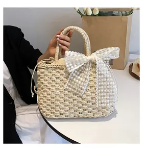 Gros plan du sac en paille tissée avec un grand nœud en dentelle et broderie de marguerites