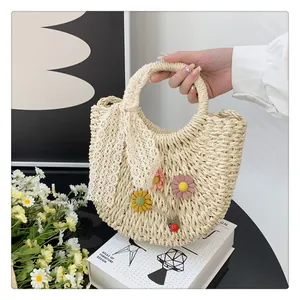 Detail of hand-woven straw bag featuring 3D fabric flowers and a lace scarf handle
