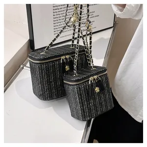 Détail du sac en paille tressée avec motif noir et blanc et fermeture éclair camélia doré