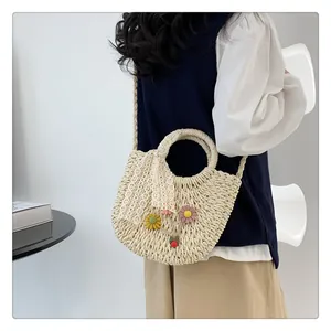 Detail of handmade straw bag with lace bow and colorful crochet flower charms
