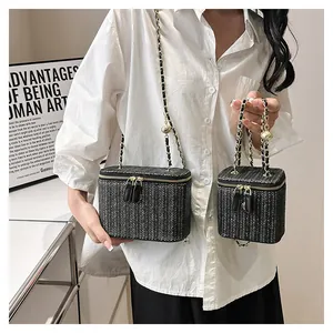 Élégant sac boîte tissé noir avec bandoulière chaîne dorée en deux tailles sur modèle