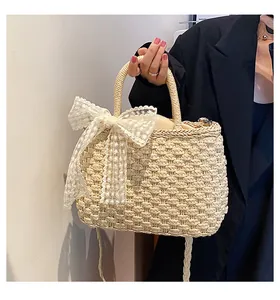 Détail d'un sac cabas en paille tissé main avec un nœud en dentelle blanche brodé
