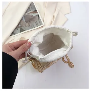 Detail van strooien tas met katoenen trekkoordsluiting en gouden kettingriem