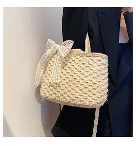 Détail du tissage de paille épais et du grand nœud en dentelle blanche sur le sac à main