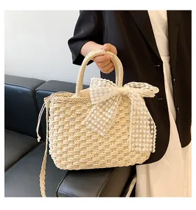 Détail du sac en paille tressée avec un grand nœud en dentelle et doublure à cordon