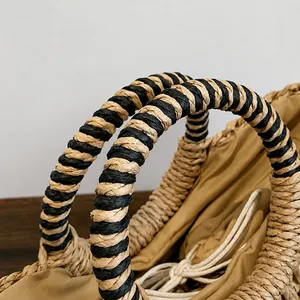 Detail eines Strohtaschen-Griffs mit schwarzen Spiralstreifen und Kordelzug-Innentasche
