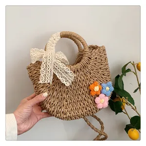 Detail of hand-woven straw handbag with white lace bow and colorful crochet flowers