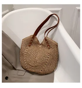Dettaglio ravvicinato della borsa tote in paglia intrecciata con manici in pelle marrone
