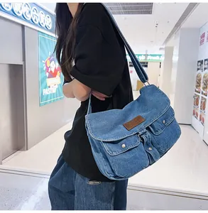 Dettaglio di una borsa a tracolla in denim vintage con due tasche frontali e fibbie metalliche