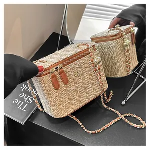 Détail du sac boîte en paille tressée à chevrons avec double zip en cuir et chaîne dorée