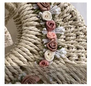 Dettaglio borsa in paglia intrecciata a mano con fiori in tessuto, pizzo e perle sintetiche
