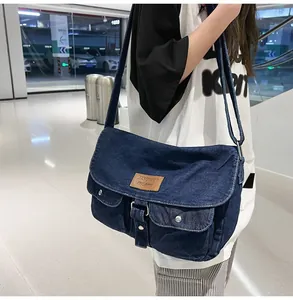 Détail du sac messager en denim bleu avec plusieurs poches et sangle réglable