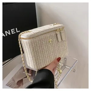 Détail du sac boîte en paille tressée avec fleur dorée et double fermeture éclair
