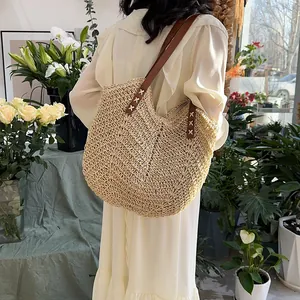 Borsa a spalla in paglia naturale con manici in pelle marrone indossata da modella