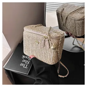 Vue détaillée d'un sac boîte en paille avec fermoir fleur dorée et bandoulière chaîne