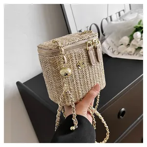 Détail du sac boîte en paille tissée beige avec chaîne dorée et camélia métallique