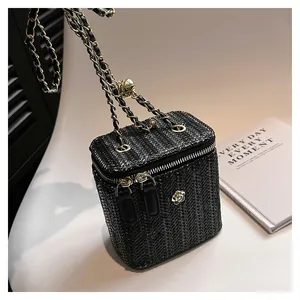 Vue détaillée du sac boîte tissé noir avec fermoir camélia doré et bandoulière