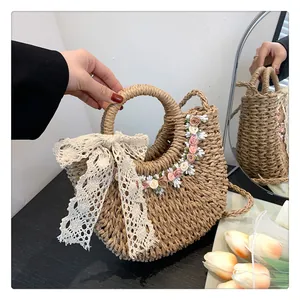 Dettaglio borsa in paglia fatta a mano con fiocco in pizzo e decorazioni floreali in tessuto